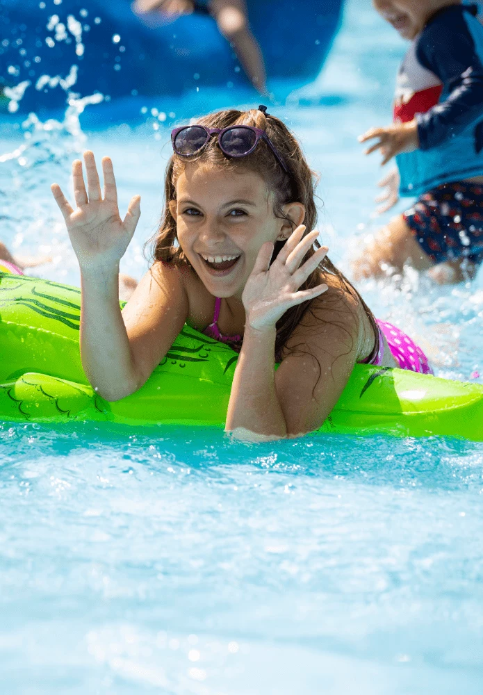 menina feliz com uma boia de jacaré na piscina